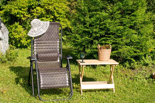 A garden chaise longue stands in the garden on the green grass with a wooden table Recreation area