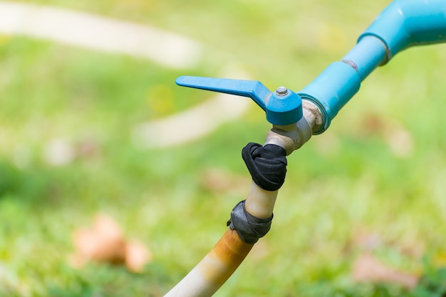 Garden hose or white rubber tube with faucet on grass field.