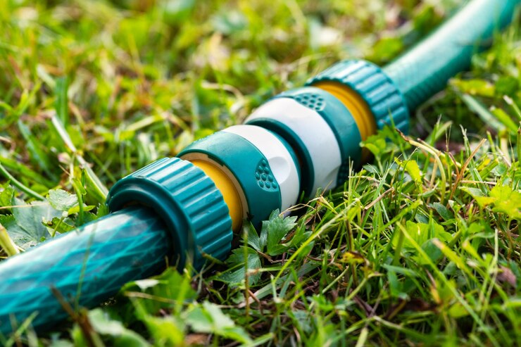 草の上にある現代のプラスチック製ホースコネクタに接続された庭の灌漑ホース