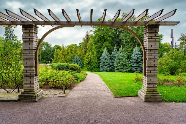 Garden Pergola With Grass Meadow And Dirt Path Between The Trees.