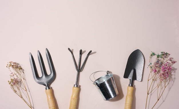 Garden shovel and metal bucket on beige background top view