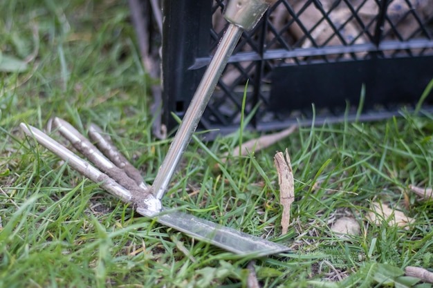 Garden tool rake chopper for gardening on the background of plastic boxes The concept of gardening and sustainable summer Metal garden tool with a rake and a hoe on a natural background