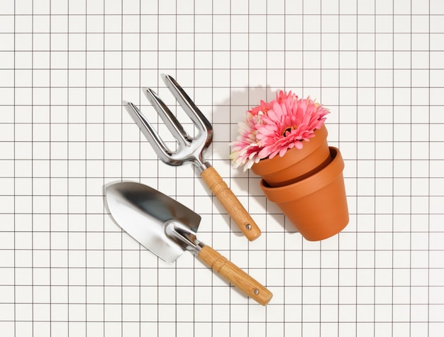 Garden tools and clay pots with beautiful flowers Flat lay Agricultural work on the plantation Small garden fork and garden shovel