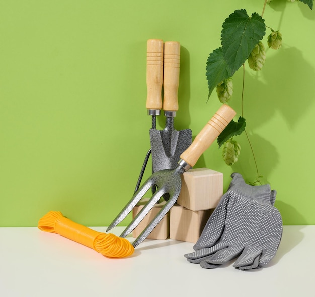 Foto attrezzi da giardino per la lavorazione di letti in giardino e guanti tessili su fondo verde