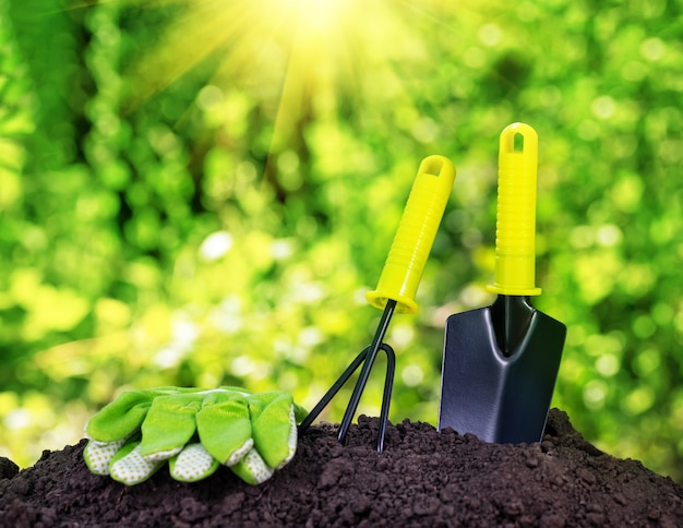 Garden tools rake trowel and gloves on pile of soil