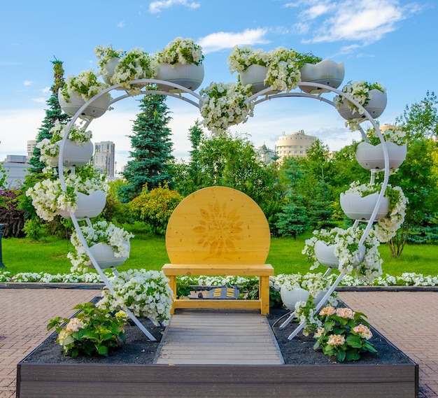 A garden with a yellow chair and a white flower arrangement.