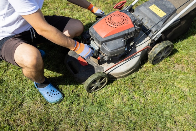 Garden worker checks lawn mower before mowing grass