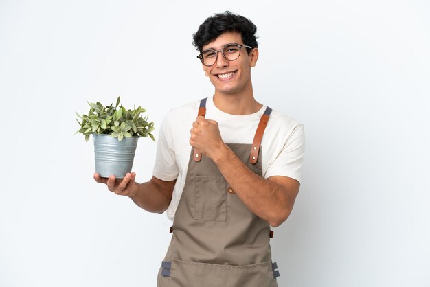 승리를 축하하는 흰색 배경에 고립 된 식물을 들고 정원사 아르헨티나 남자