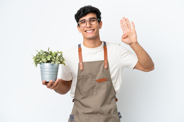 Gardener Argentinian man holding a plant isolated on white background happy and counting four with fingers