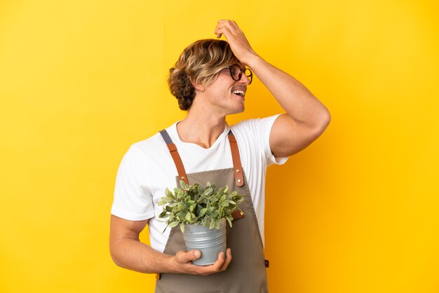 Gardener blonde man holding a plant isolated