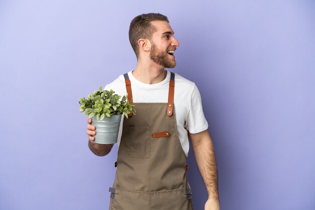 Gardener caucasian man holding a plant isolated