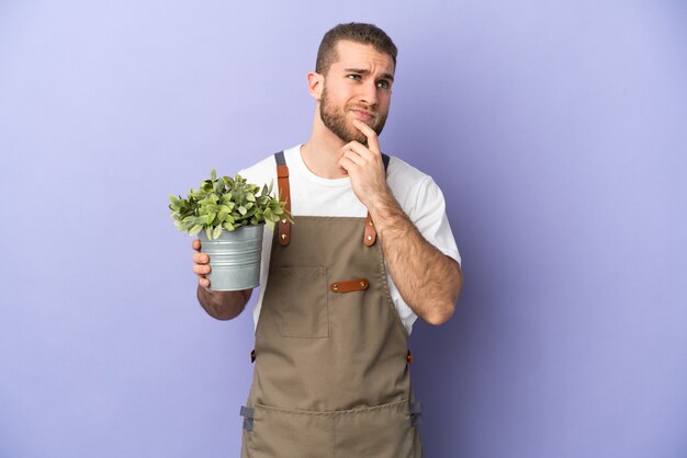 Gardener caucasian man holding a plant isolated