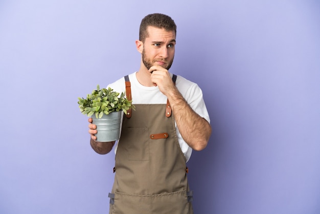 Gardener caucasian man holding a plant isolated