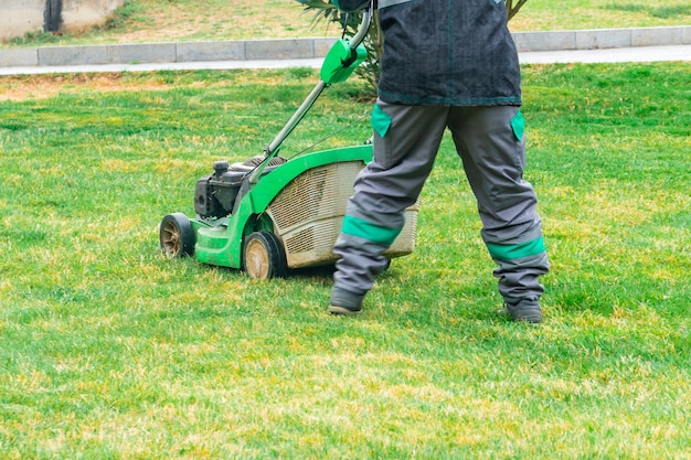 Photo the gardener cutting grass by lawn mower