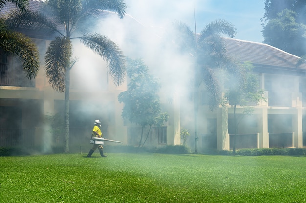 gardener doing a poisoning activity by spraying insecticide or pesticides to control the insects in a hotel.