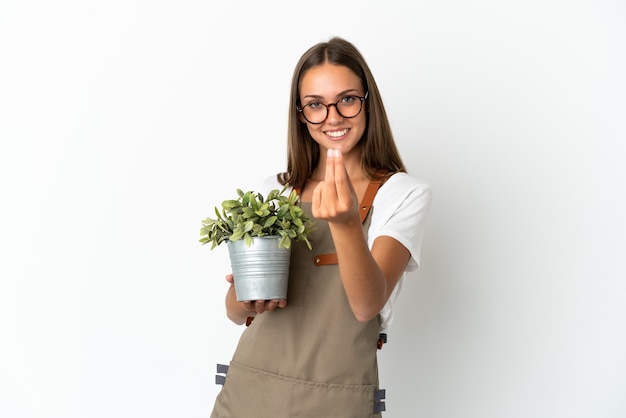 お金のジェスチャーを作る孤立した白い背景の上に植物を保持している庭師の女の子