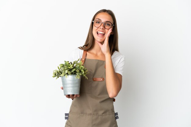 Девушка-садовник держит растение на изолированном белом фоне и кричит с широко открытым ртом