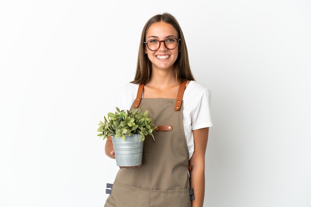 驚きの表情で孤立した白い背景の上に植物を保持している庭師の女の子