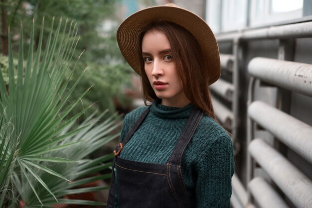 Gardener in hat and apron against green plants