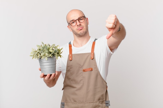 Gardener man feeling cross, angry, annoyed, disappointed or displeased, showing thumbs down with a serious look