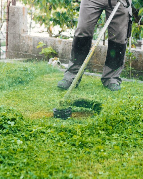 Giardiniere che falcia l'erba