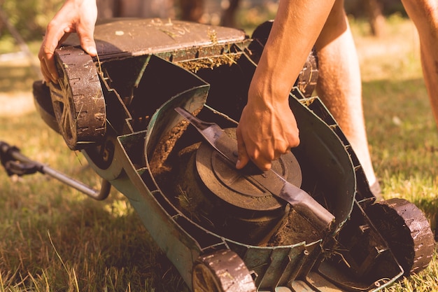 Gardener repairs and fixes the a lawn mower in garden