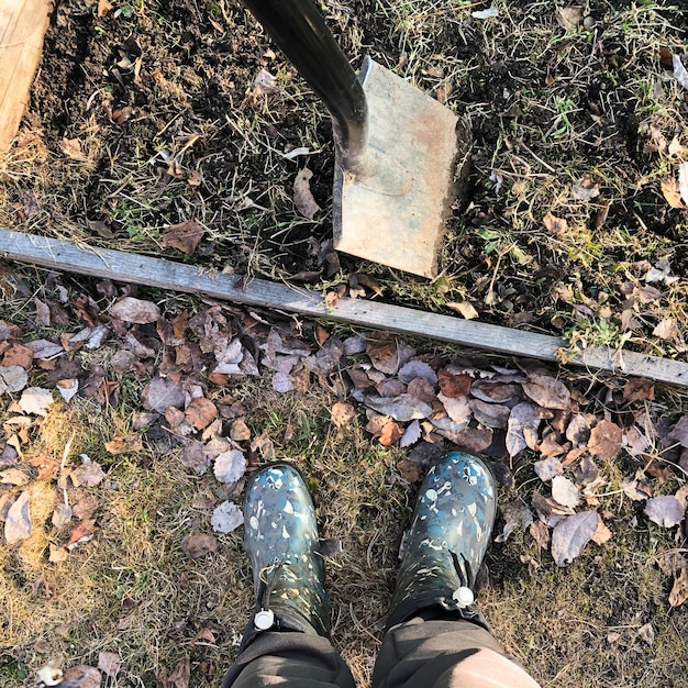 Photo a gardener's feet in rubber boots and a shovel on a bed of soil