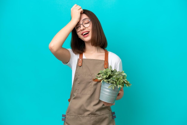 青の背景に植物を保持している庭師のウクライナ人女性は、何かを実現し、解決策を考えています