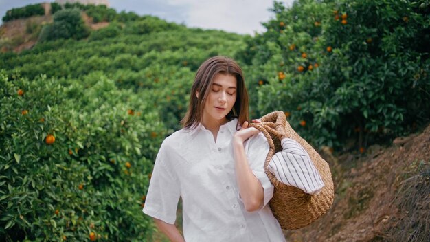 Gardener woman holding basket in green hills plantation zoom on lady posing