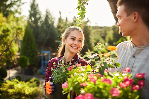 Gardeners happy boy and girl hold pots with plants in beautiful gardens on a warm sunny day .