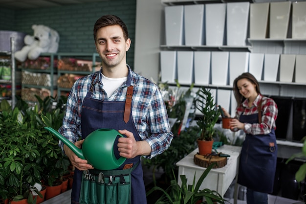 Gardeners happy boy and girl holding pots with plants in beautiful garden center