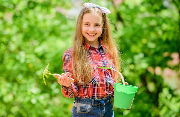 Foto corsi di giardinaggio educazione all'ecologia bambina che pianta piante stagione di semina cura del giardino bambino adorabile bambino tenere vaso di fiori e zappa strumento di giardinaggio il giardinaggio è un'occupazione pacifica e meditativa