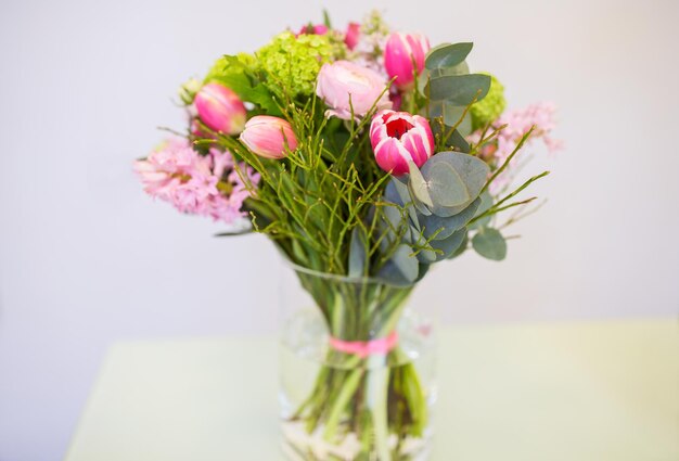 gardening, floristry, holidays and flora concept - close up of bunch in vase at flower shop