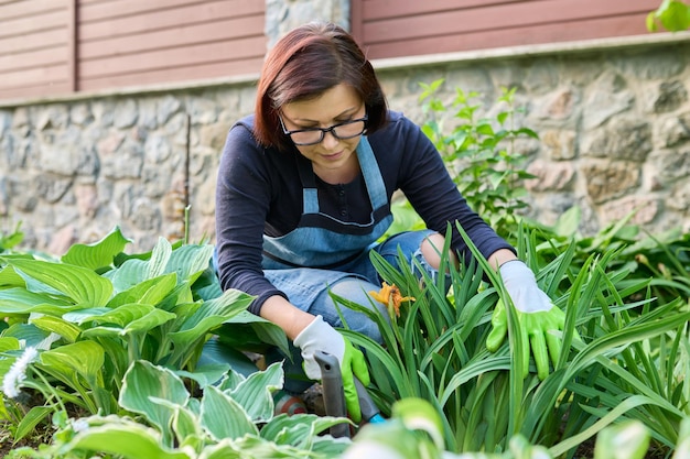 Садоводство клумб женщина-садовник, работающая с растениями в саду
