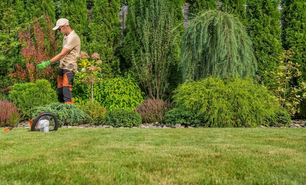 Gardening Industry Theme Caucasian Professional Garden Worker in His 40s Performing Seasonal Garden Maintenance