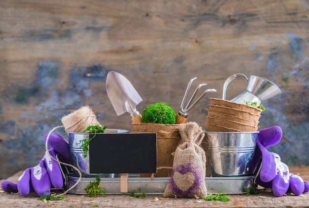 Gardening tools, pots and utensils on rustic wooden background, with a chalk board