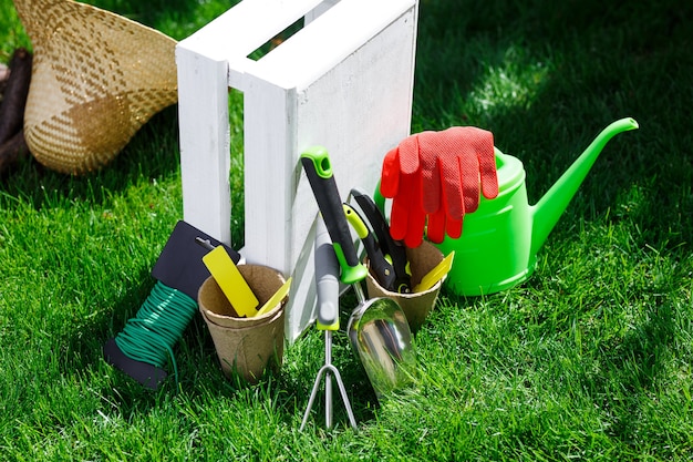 Photo gardening tools and a straw hat on the grass in the garden.