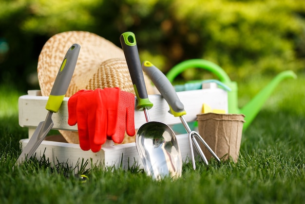 Photo gardening tools and a straw hat on the grass in the garden.