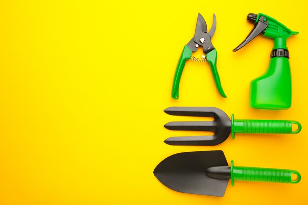 Gardening tools on yellow background, top view