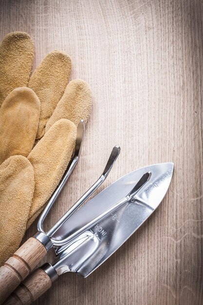 Gardening trowel fork with shovel and leather safety gloves on wooden background vertical version agriculture concept
