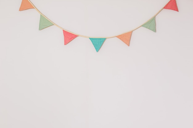 Photo garland of cute party flags hanging on the wall. background with copyspace symbolising home celebration, birthday or festive mood