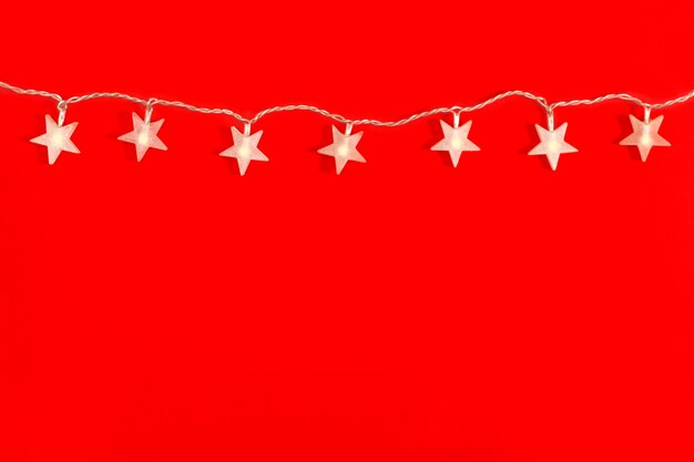 Garland in the form of star, festive decorations on a red background with copy space. Christmas concept. Flat lay, top view