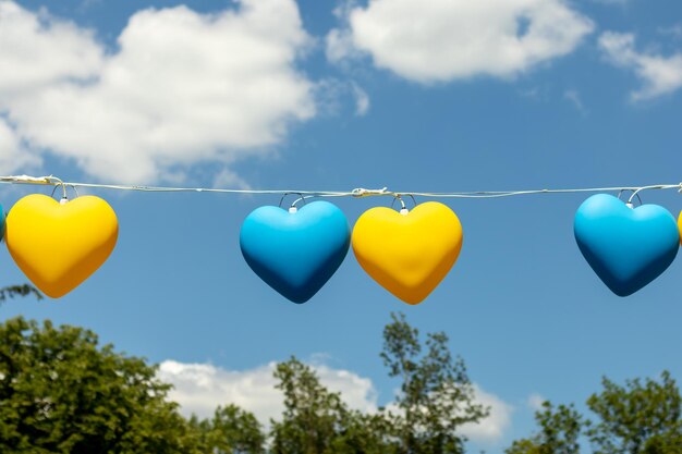 Garland in the form of yellow and blue hearts against the blue sky The concept of support for Ukraine