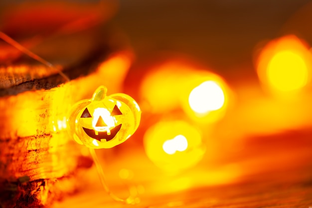 Garland of glowing halloween pumpkins on dark wooden background with copy space. Halloween background.