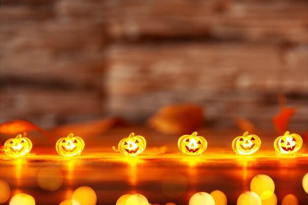 Photo garland of glowing halloween pumpkins on dark wooden background with copy space. halloween background.