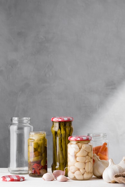 Photo garlic, asparagus and olives preserved in glass jars with copy space