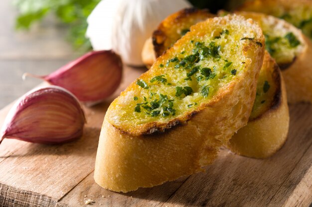 Garlic breads slice and ingredients on wooden table close up