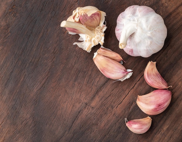 Garlic bulb and cloves over wooden table with copy space