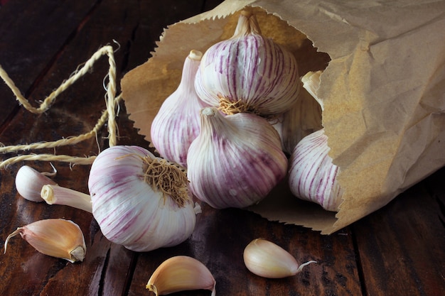 Garlic bulbs on packing paper, on rustic wooden table