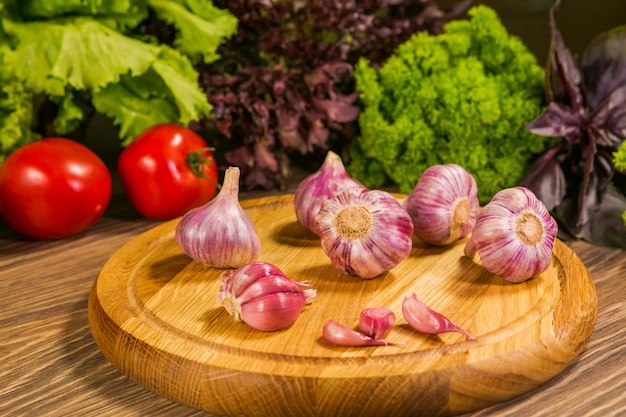 Garlic bulbs on a wooden board with a green salad 